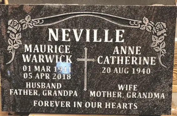 Dark granite companion flat marker with roses in both top corners, a central cross, two names with dates and an epitaph