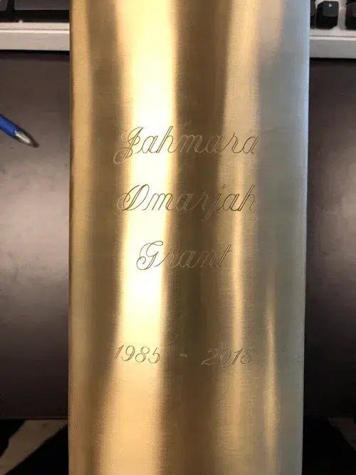 Diamond Engraving on Brushed Brass Urn Diamond engraved script name and years on a brushed brass metal urn, close up of the engraving detail
