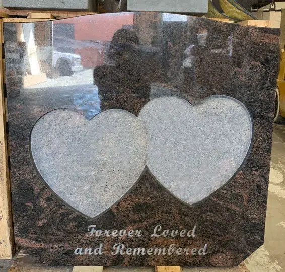 Reddish brown granite upright headstone with two overlapping frosted heart panels and a script epitaph