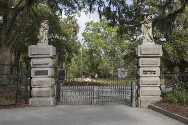 Entrance to Bonaventure Cemetery in Savannah: two grey stone pillars topped with white statues and a black iron gate