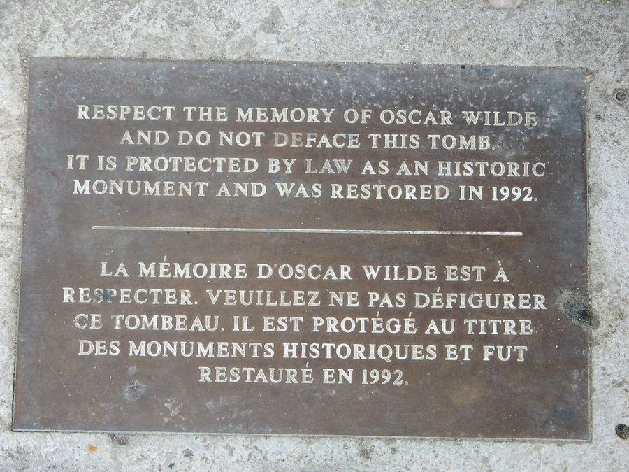 Metal plaque in English and French set in pale stone, asking visitors not to deface the tomb, Père Lachaise Cemetery, Paris