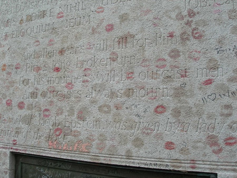 Carved verse on the back of a pale stone tomb, covered in red and pink lipstick kiss marks, Père Lachaise Cemetery, Paris