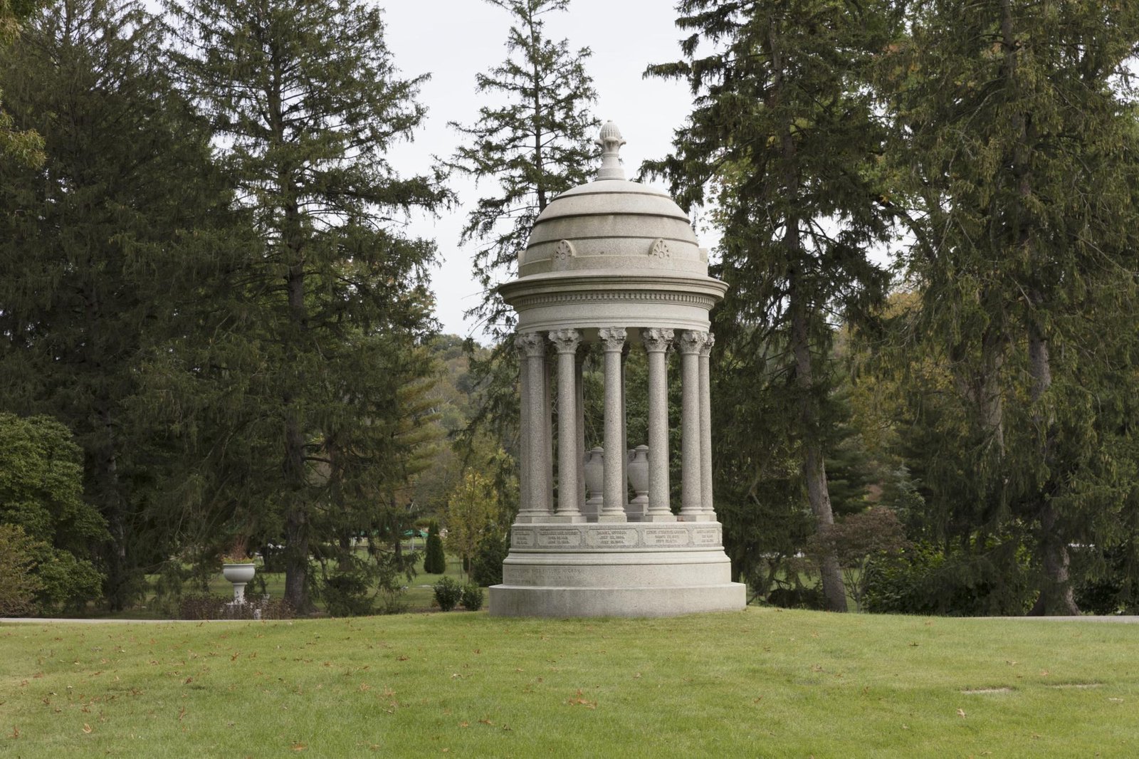 Pale stone family monument with a domed roof on a ring of columns and two urns inside at Spring Grove Cemetery, Cincinnati