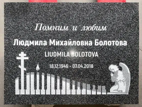 Dark grey granite flat marker with an Orthodox cross, candle, piano keys and kneeling angel, plus a name and dates