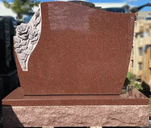 Indian Red granite serpentine headstone with carved rose cluster on a rock pitched base