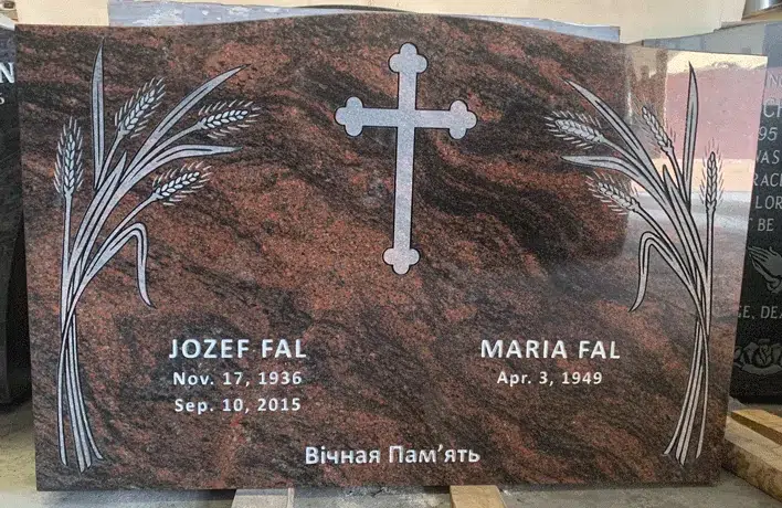Mahogany granite upright headstone with an engraved cross and wheat sheaves, English and Ukrainian inscription